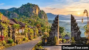 Jalan batu di desa wisata dengan rumah tradisional, pepohonan hijau, dan taman yang tertata rapi.